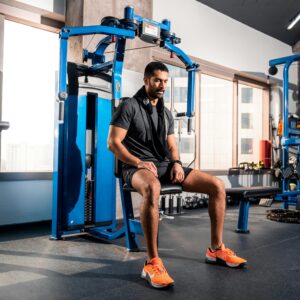 Adult man exercising on gym equipment in a modern gym located in Bahrain.